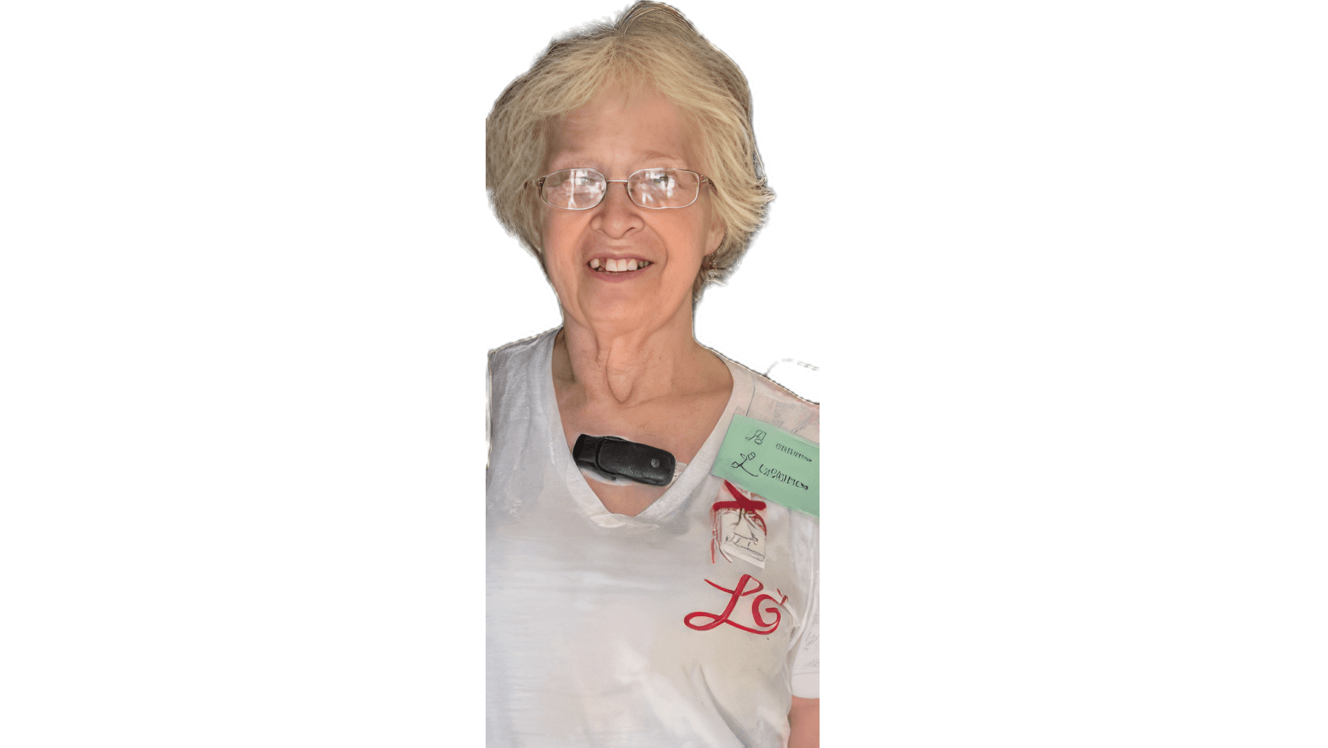 Smiling senior woman with blonde hair and glasses wearing a medical sensor on her shirt.